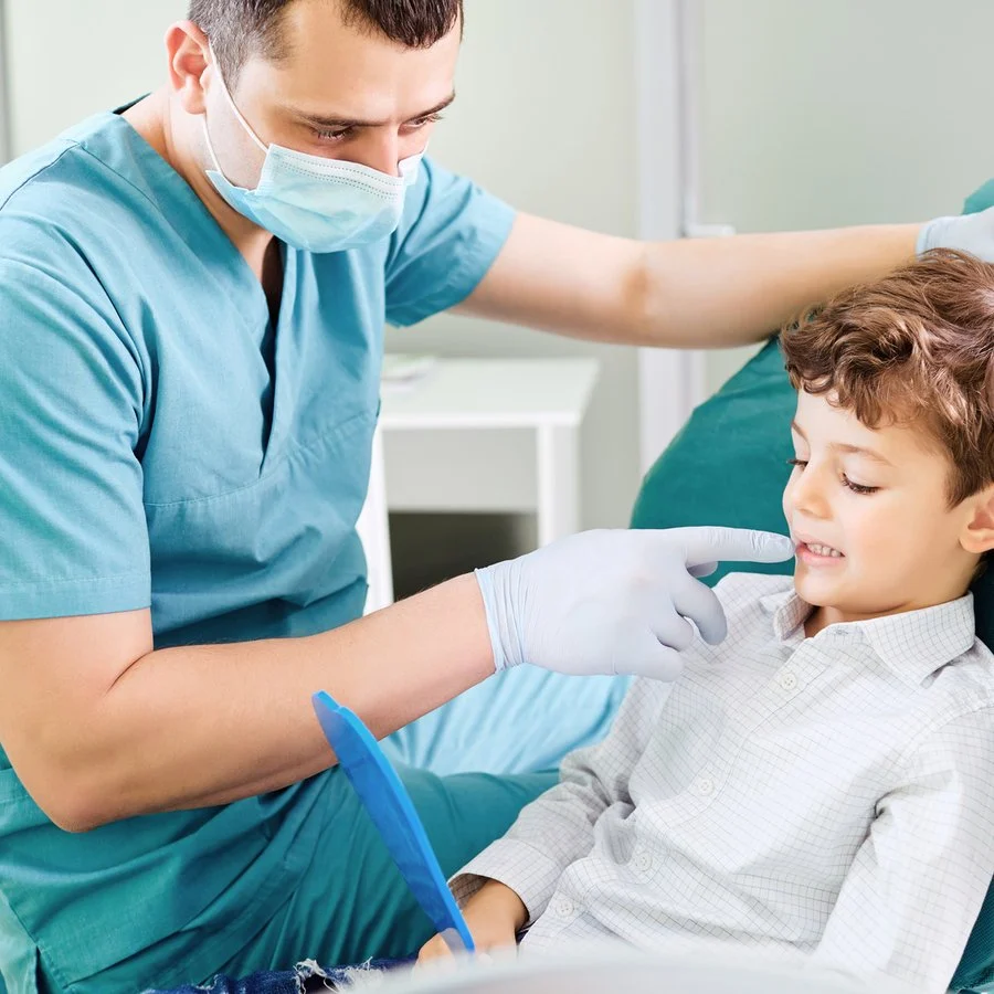 Dentist and young boy checking teeth with a hand mirror