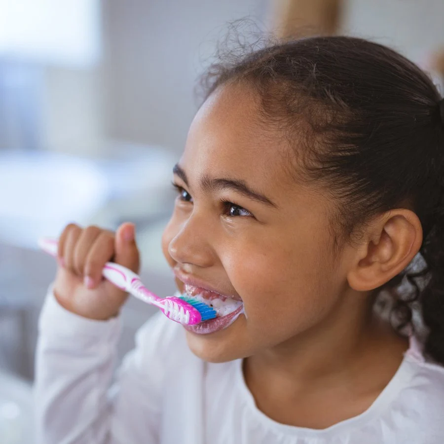 Smiling girl brushing her teeth in the bathroom