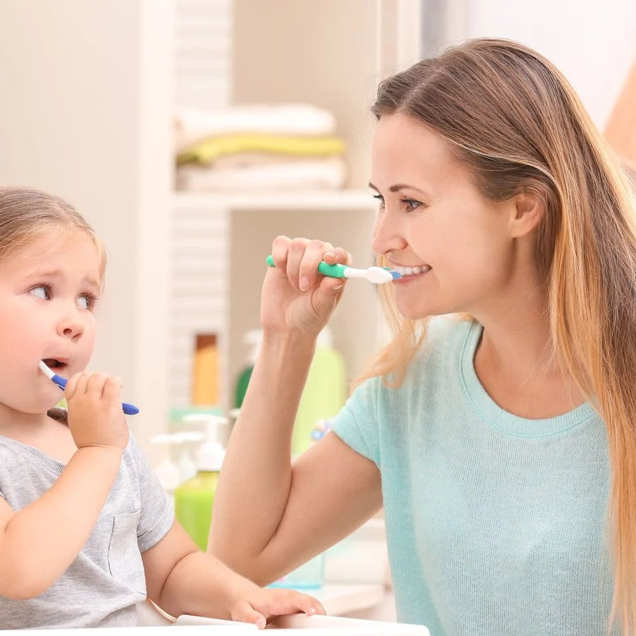 Mother and daughter brushing their teeth together